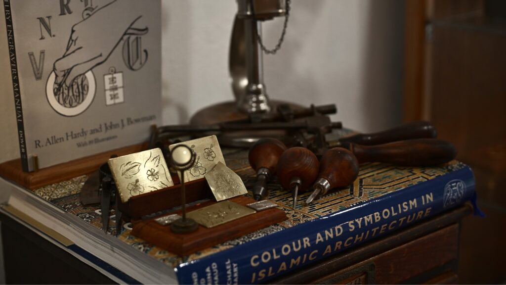Jewellery-making tools and hand-engraved design samples on a workbench