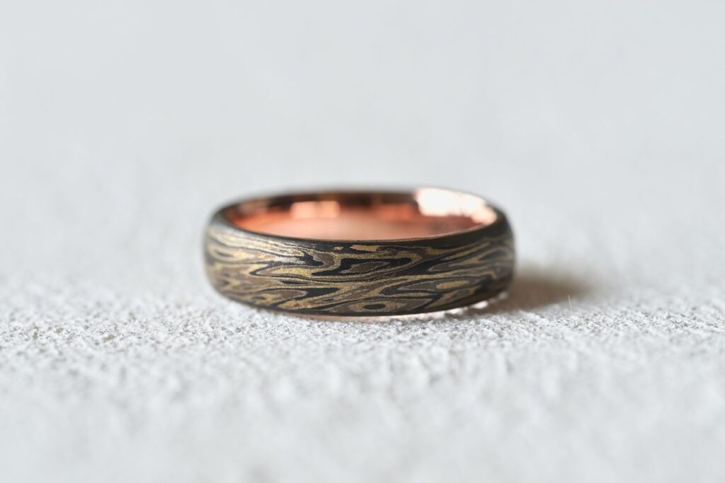 Mokumegane ring featuring an oxidised finish that enhances the layered grain pattern