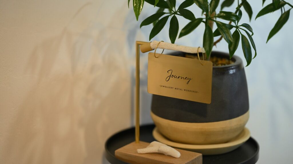 Journeyのロゴが刻まれた金属製サインプレートと植物