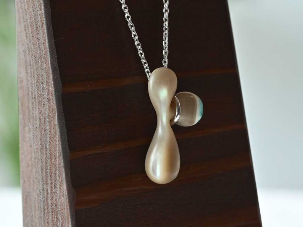 Memory of the Okinawan Sea pendant featuring a flowing organic shape carved from green turbo shell
