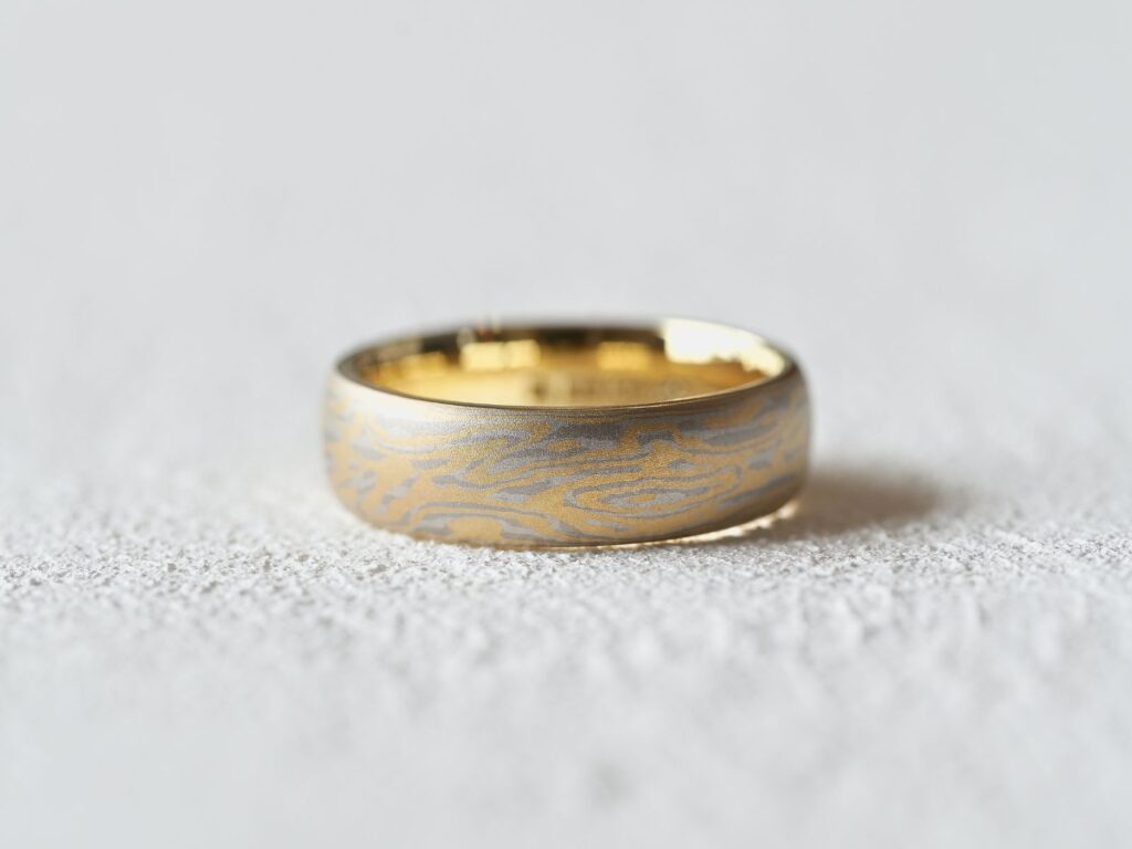 Moire Mokumegane ring featuring flowing gold and silver woodgrain patterns