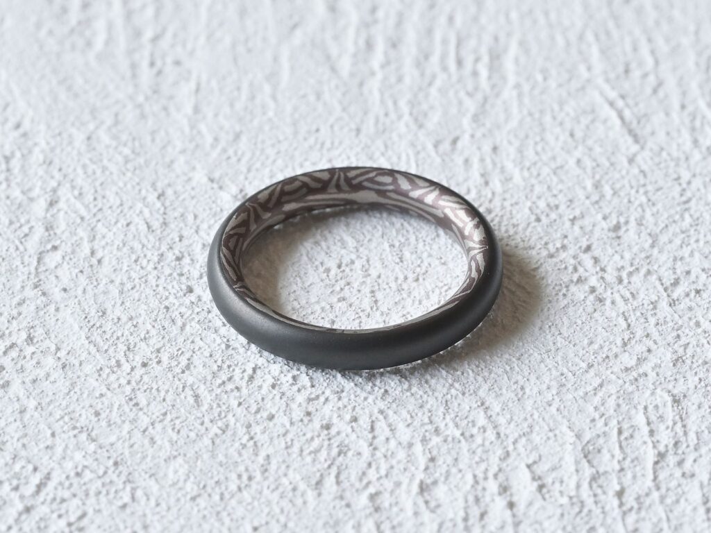 Tribal ring featuring a matte black tantalum exterior and Mokumegane interior