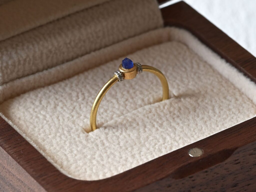 Primitive ring featuring a rough sapphire set in 18K green gold and platinum