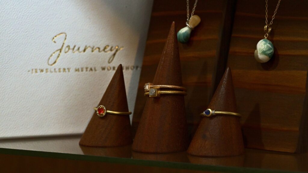 Display of Journey jewellery including rings and green turbo shell pendants