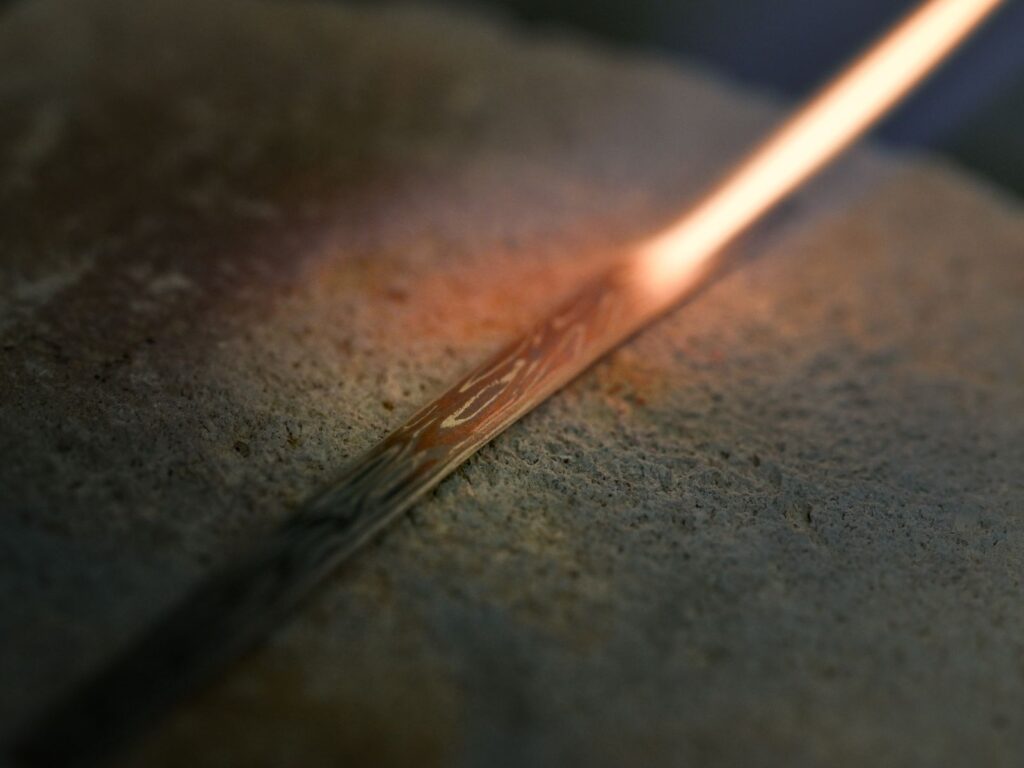 Heated Mokumegane metal revealing a unique wood-grain pattern created from layered precious metals
