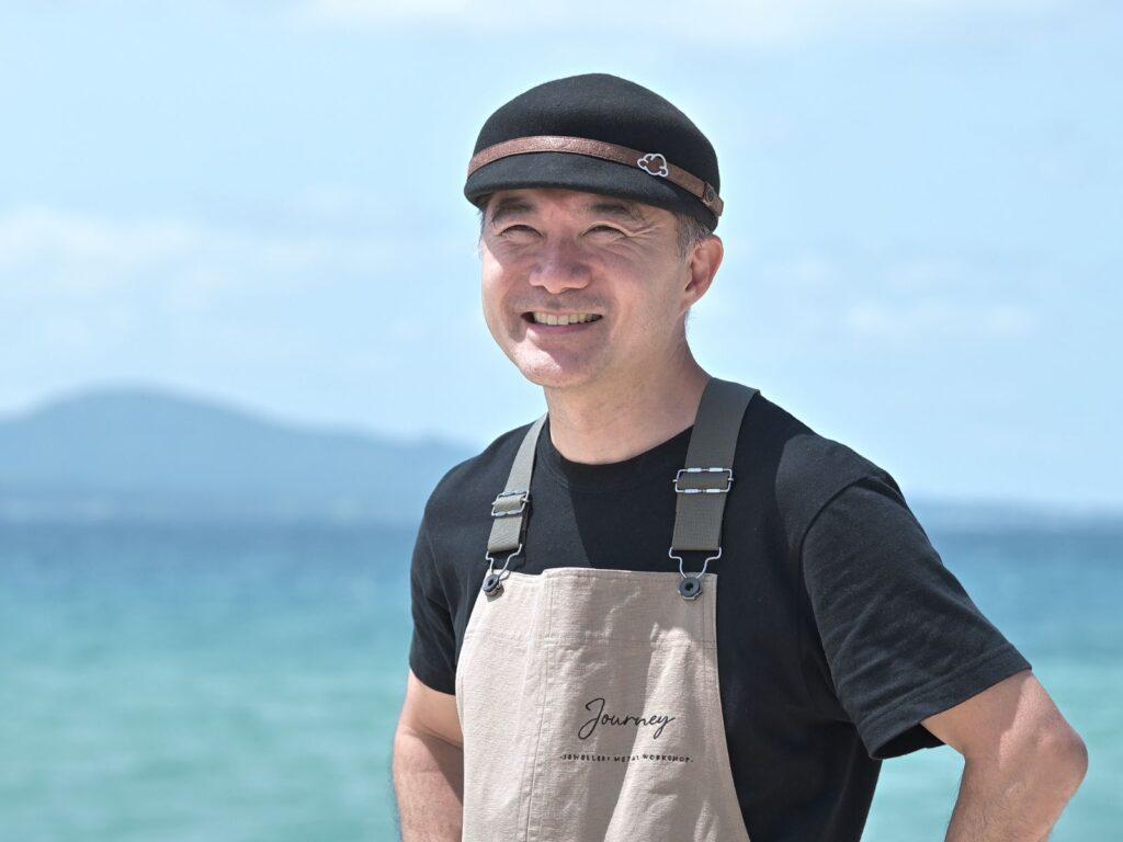 Asato, founder and jeweller at Journey, photographed by the sea in Okinawa
