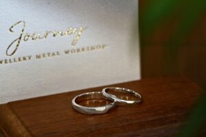 Pair of wedding bands displayed beside a Journey jewellery box