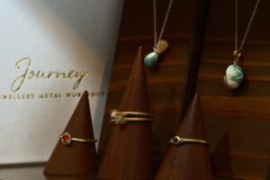 Journey jewellery display featuring rings, green turbo shell pendants and a branded jewellery box
